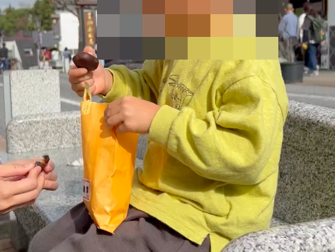 成田山参道のベンチで栗を食べる息子の写真。