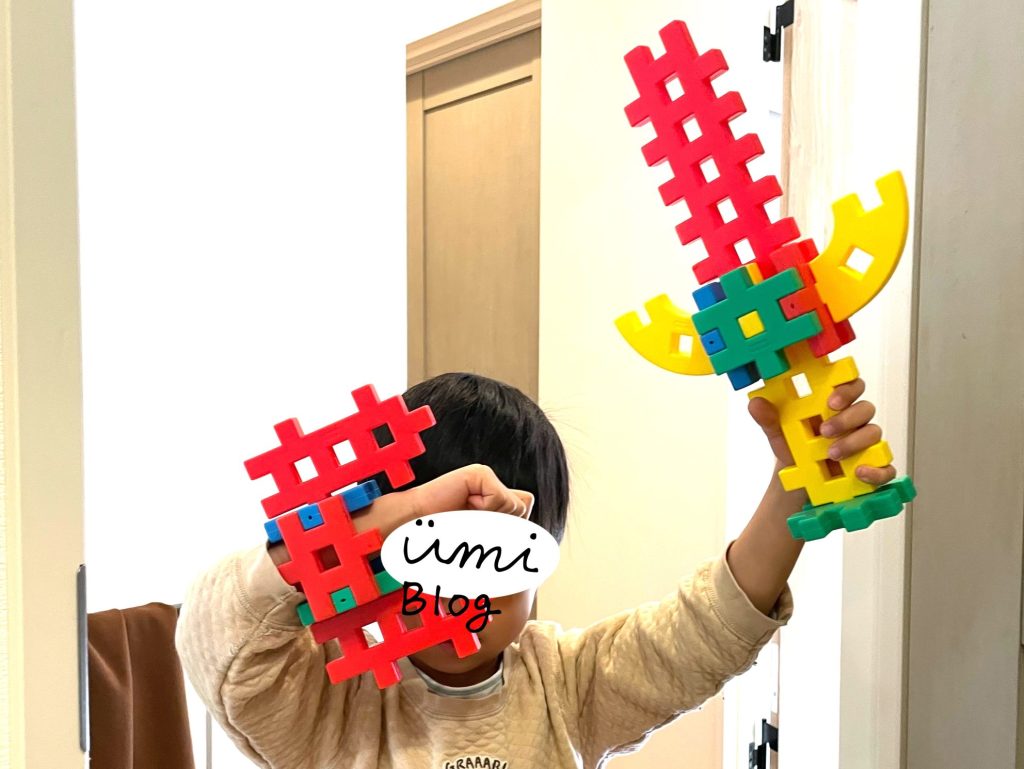 ニューブロックでつくった剣と盾をかざす息子の写真
